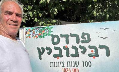 עו״ד שמואל רביב רבינוביץ על רקע שלט: פרדס רבינוביץ. 100 שנות ציונות מאז 1924