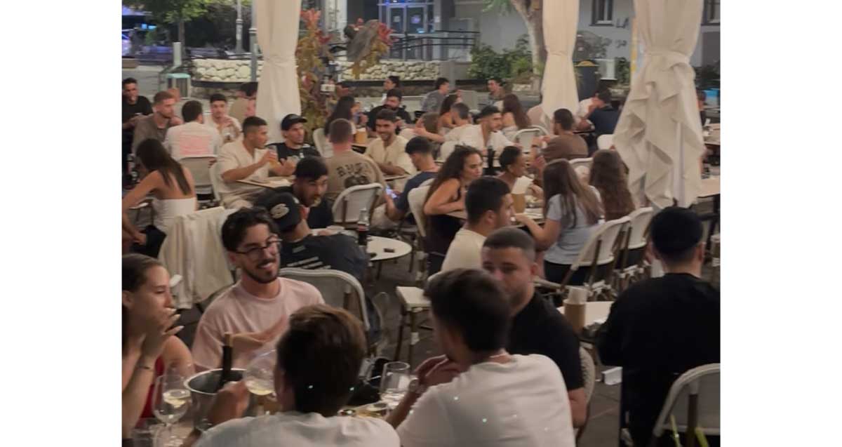 רוטשילד של היום. קפה רוטשילד תוסס. צעירות וצעירים יושבים ליד שולחנות בצפיפות.