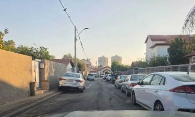 רחוב צר עם מדרכות צרות בראשון לציון. רכבים חונים שני צידי הכביש, חלקם עם שני גלגלים על המדרכה הצרה